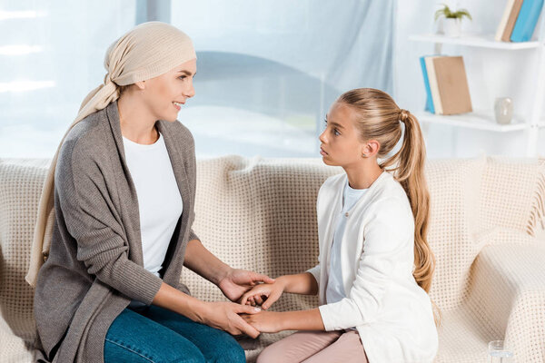 sick mother holding hands with cute daughter at home 