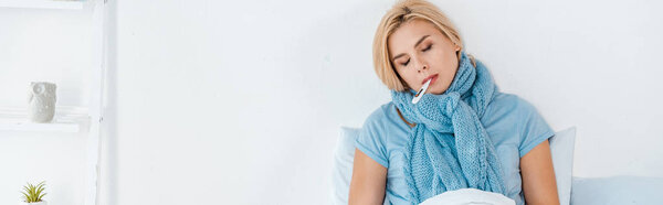 panoramic shot of sick woman holding digital thermometer in mouth