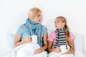 nemocnou matku a dceru, která odpočívá v posteli a drží šálky s čajem 