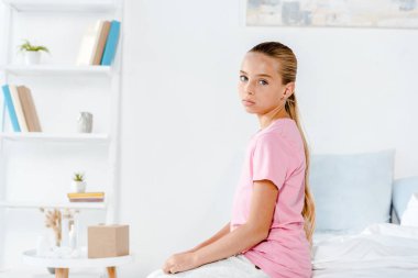 üzgün çocuk yatakta oturan ve kameraya bakarak 