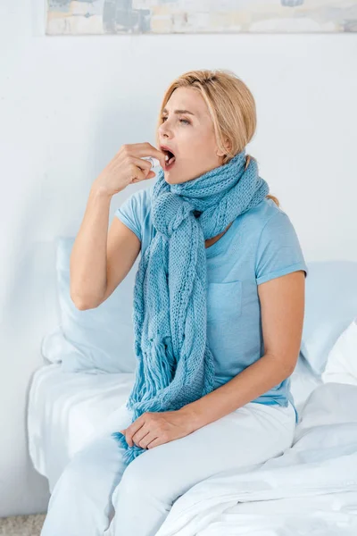 ベッドに座っている間に錠剤を服用するスカーフの病気の女性 — ストック写真