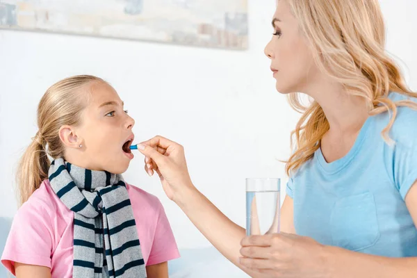 母亲拿着一杯水 用张开的嘴给生病的女儿服用药丸 — 图库照片