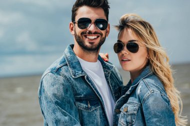 attractive woman and handsome man in denim jackets looking at camera  clipart