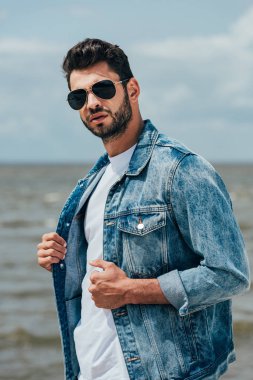 kot ceket ve güneş gözlüğü yakışıklı adam kameraya bakarak 