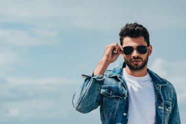 handsome man in denim jacket and sunglasses looking at camera  clipart