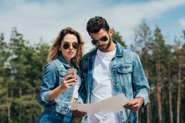 akıllı telefon tutan çekici kadın ve haritaya bakarak yakışıklı adam