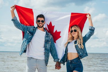 blonde woman and man in jacket holding canadian flag  clipart