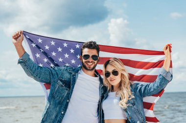 çekici kadın ve yakışıklı adam gülümseyerek ve Amerikan bayrağı tutarak 