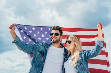 çekici kadın ve yakışıklı adam gülümseyerek ve Amerikan bayrağı tutarak 