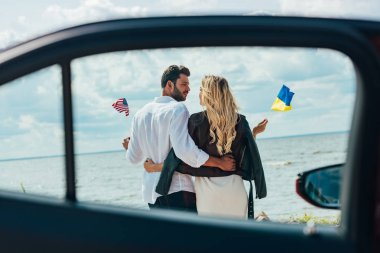 Amerikan ve Ukrayna bayrakları tutan kadın ve erkek geri görünümü 