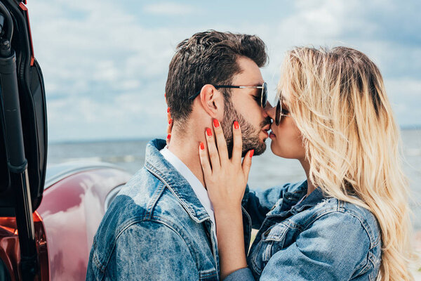 attractive woman and handsome man in denim jackets kissing outside 
