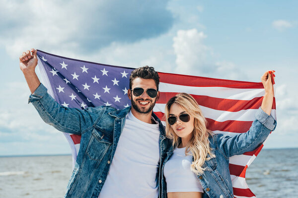привлекательная женщина и красивый мужчина улыбается и держит американский флаг
 