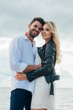 çekici kadın ve yakışıklı adam gülümseyerek ve dışarıda sarılma 