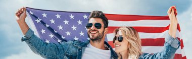 çekici kadın ve yakışıklı adam gülümseyen ve Amerikan bayrağı tutan panoramik çekim 