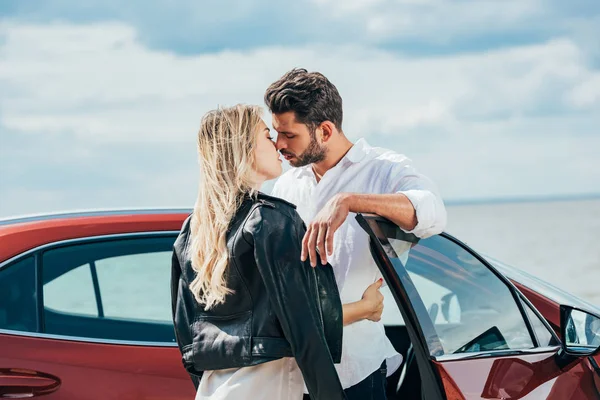 魅力的な女性とハンサムな男性が車の近くでキスして抱きしめる — ストック写真