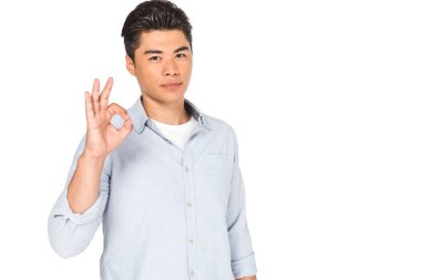 beyaz izole kamera bakarken tamam işareti gösteren genç asyalı adam