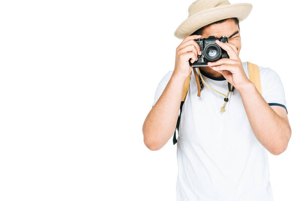 young asian man in hat taking photo on digital camera isolated on white