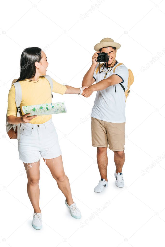 young asian tourist taking photo of girlfriend holding map on white background