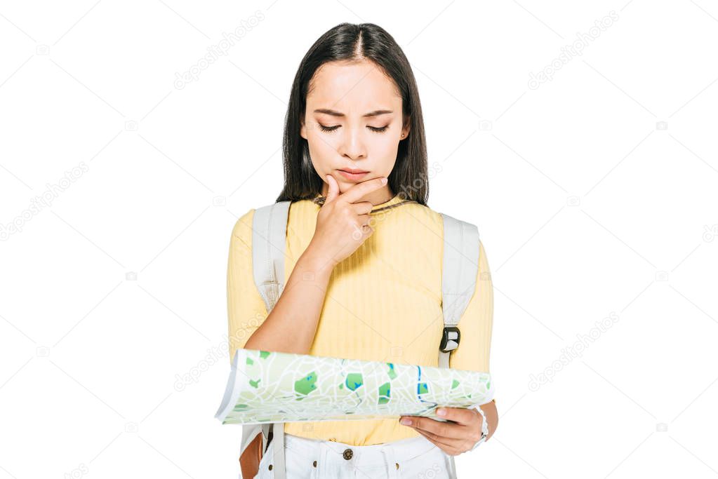 thoughtful asian girl holding hand near face while looking at map isolated on white