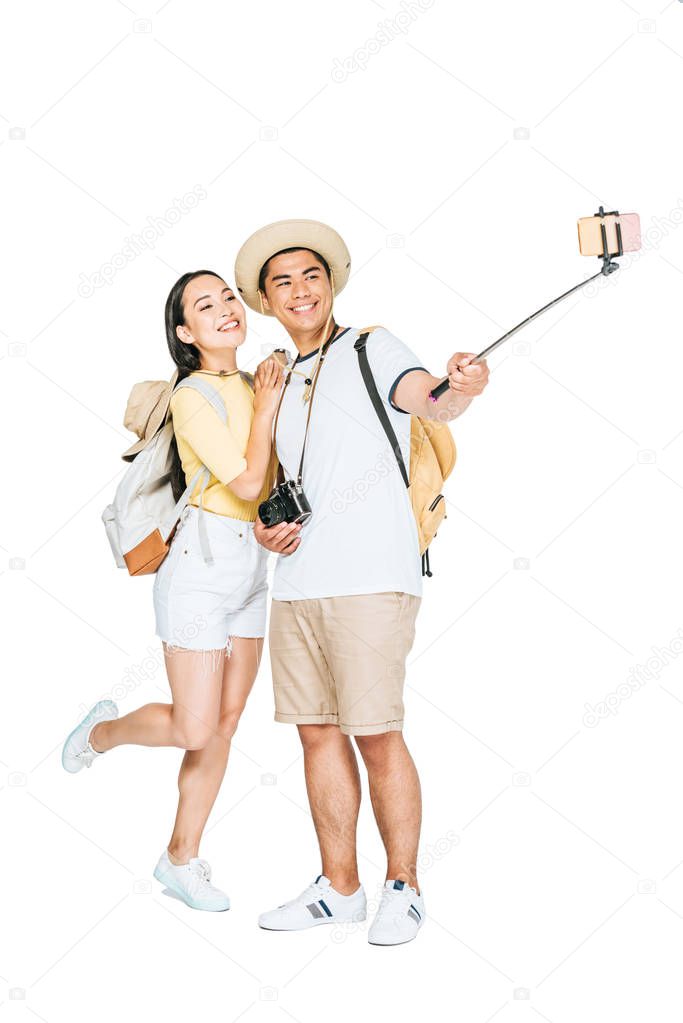 two young asian tourists taking selfie on smartphone with selfie stick on white background