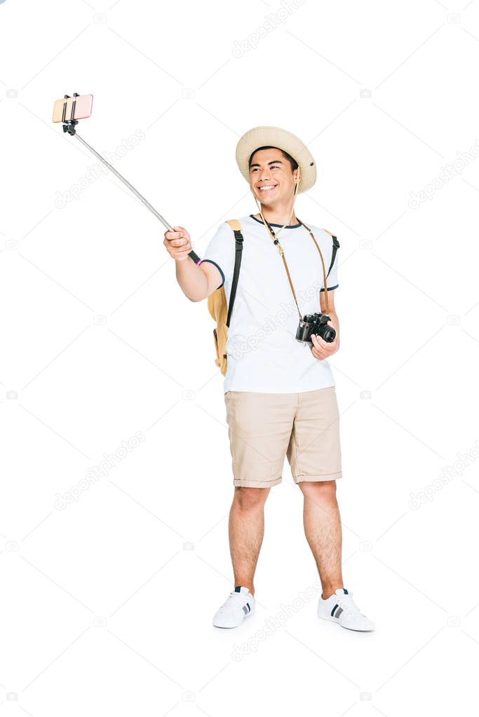 happy asian man taking selfie on smartphone with selfie stick on white background