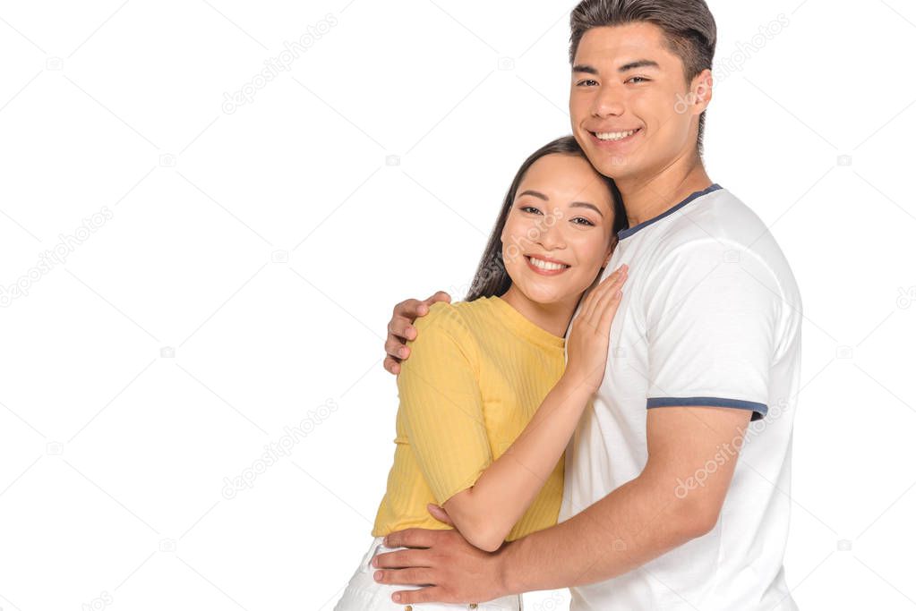 happy asian couple embracing and smiling at camera isolated on white