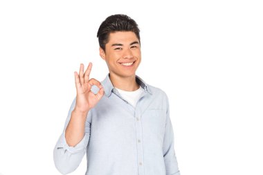 happy asian man showing okay sign while smiling at camera isolated on white clipart