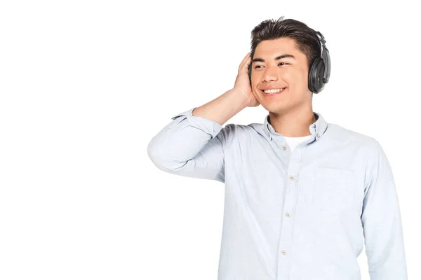 ヘッドフォンで音楽を聴く陽気なアジア人男性 笑顔で白に孤立した目をそらす — ストック写真