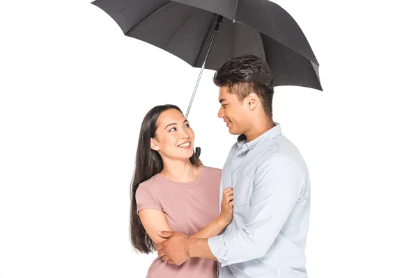 幸せなアジアのカップルは 白い上に孤立した傘の下に立っている間 抱きしめてお互いを見つめる — ストック写真
