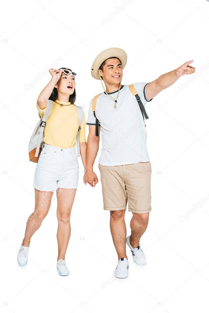 two young asian tourists holding hands and looking away on white background