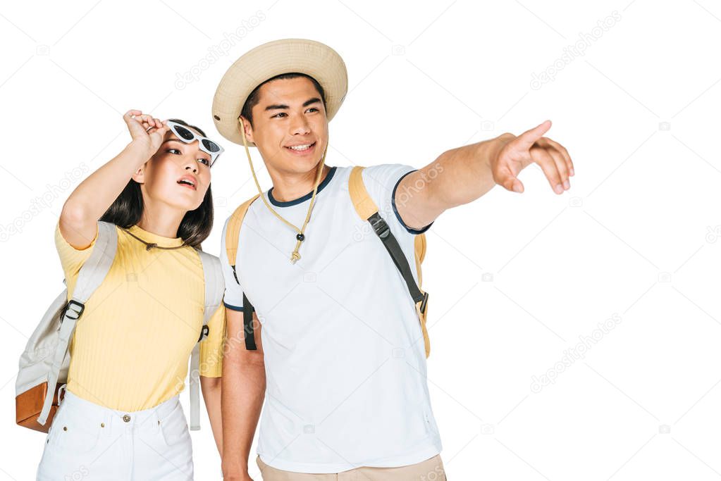 handsome asian man pointing with finger while holding hands with pretty girlfriend isolated on white