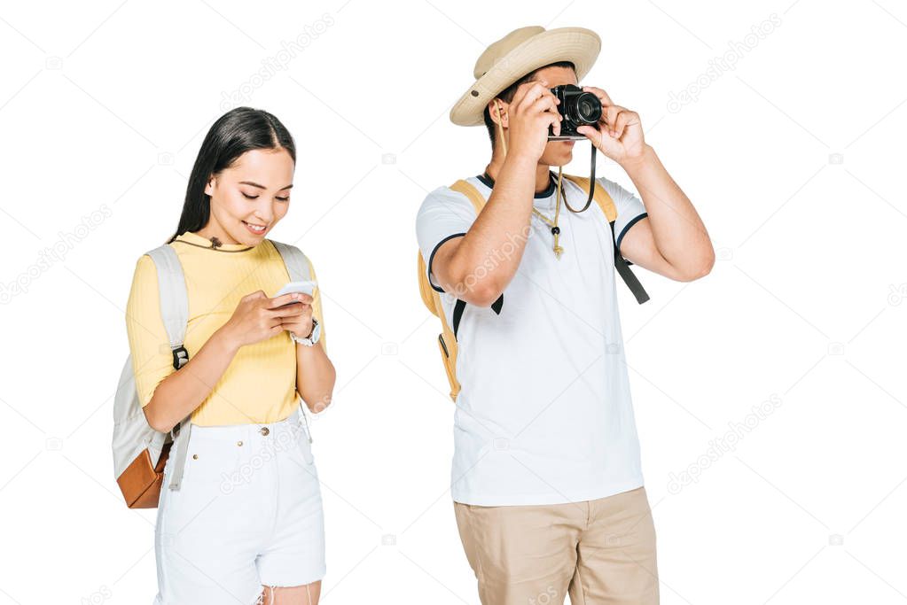 asian tourists taking photo on digital camera near girlfriend using smartphone isolated on white