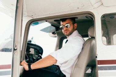 uçakta beyaz gömlek ve güneş gözlüğü yakışıklı pilot