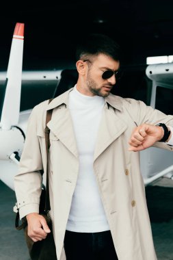 şık işadamı ceket uçak yanında duran ve kol saati bakıyor