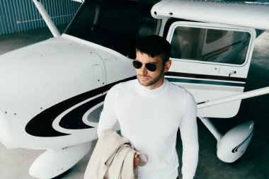 güneş gözlüğü ve rahat kıyafetleri uçağın yanında duran ve uzağa bakan adam yüksek açı görünümü