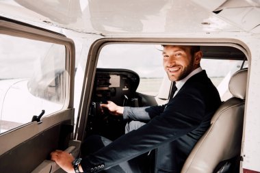 uçakta oturan ve tutan resmi giyim gülümseyen pilot 