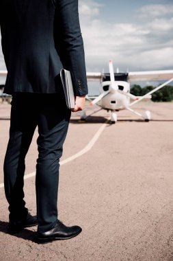 güneşli bir günde dizüstü bilgisayar ve harita tutan resmi giyim işadamı kısmi görünümü