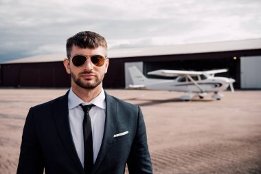 resmi giyim ve güneş gözlüğü uçağın yanında duran ciddi işadamının ön görünümü