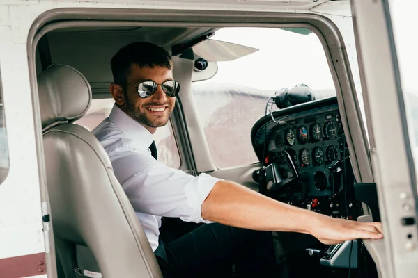 Lächelnder Gutaussehender Pilot Mit Sonnenbrille Blickt Flugzeug Die Kamera — Stockfoto