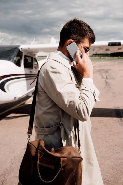 Vista Lateral Homem Casaco Com Saco Falando Smartphone Perto Avião — Fotografia de Stock