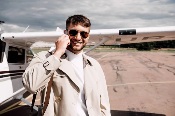 Hombre Sonriente Abrigo Con Bolsa Hablando Teléfono Inteligente Cerca Avión — Foto de Stock