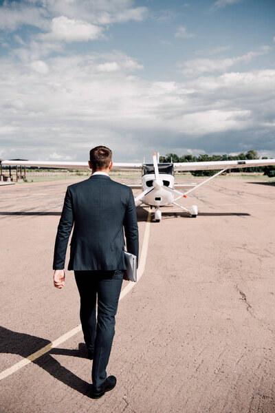 назад взгляд бизнесмена в формальной одежде, держащего ноутбук и карту в солнечный день
