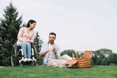 parkta engelli kız arkadaşı ile istirahat ederken dijital tablet kullanarak yakışıklı genç adam
