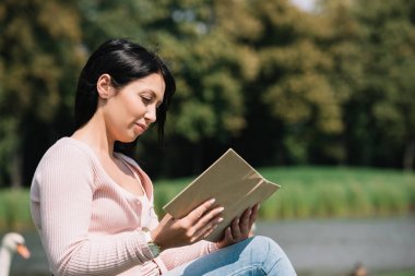 parkta kitap okurken gülümseyen genç engelli kadın