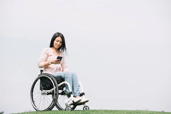 Parkta Dinlenirken Akıllı Telefon Kullanarak Tekerlekli Sandalyede Gülümseyen Engelli Kadın — Stok fotoğraf