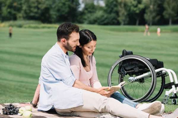 Livro Leitura Feliz Com Namorada Deficiente Enquanto Sentado Cobertor Parque — Fotografia de Stock