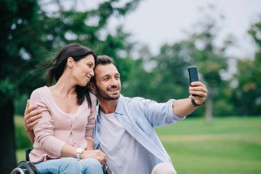 parkta akıllı telefonda engelli kız arkadaşı ile selfie çeken mutlu adam