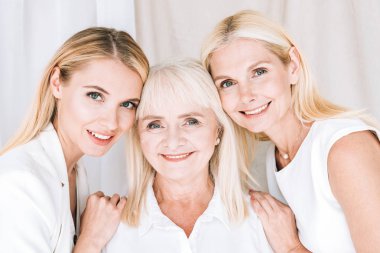 elegant three-generation blonde women in total white outfits clipart