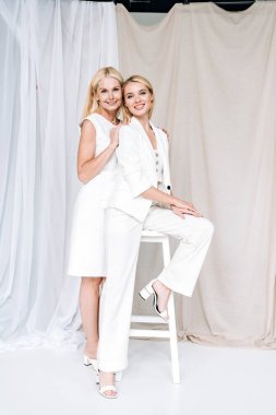 gülümseyen zarif sarışın olgun anne yavaşça sandalyede genç kızı sarılma