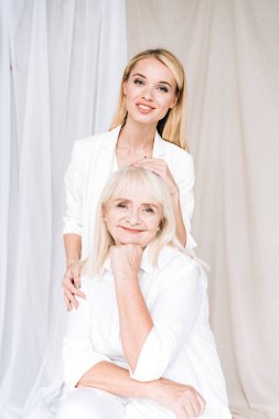 toplam beyaz kıyafetler birlikte gülümseyen sarışın büyükanne ve torunu